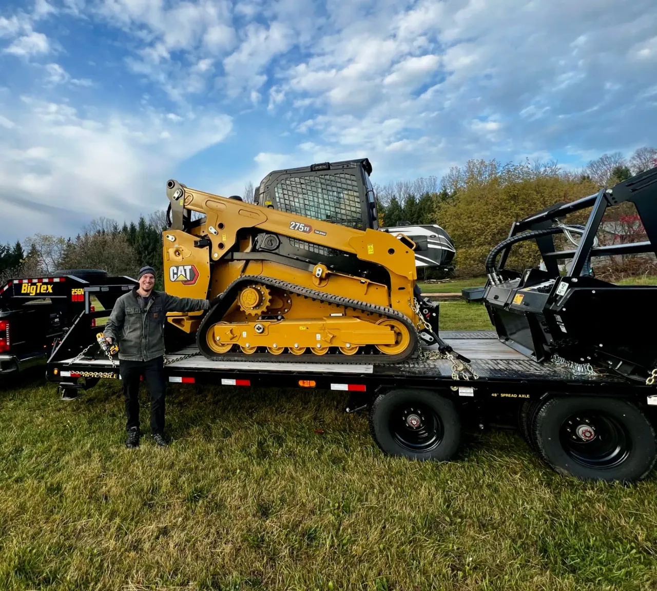 Owner of Truax Land Clearing standing next to CAT 275 XE compact track loader on trailer in Northeast Wisconsin