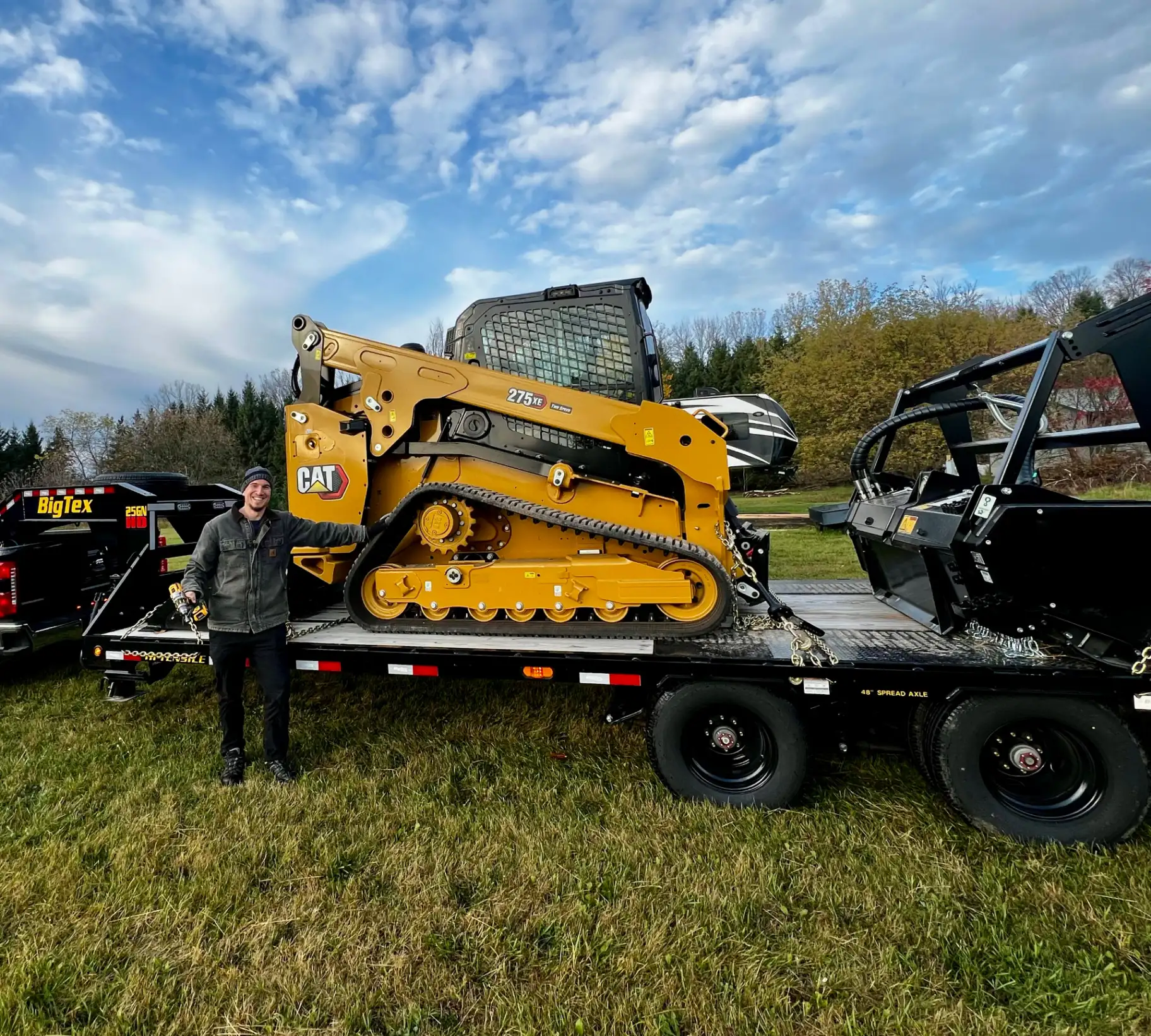 Owner of Truax Land Clearing standing next to CAT 275 XE compact track loader on trailer in Northeast Wisconsin